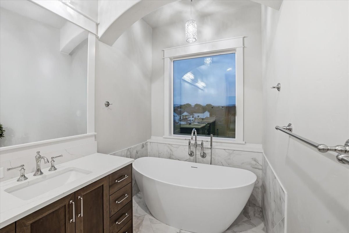 Freestanding soaking tub beside a marble-topped vanity in a custom home bathroom