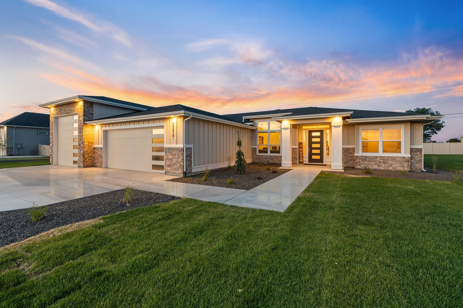 Single-story custom home at dusk with a landscaped lawn and walkway