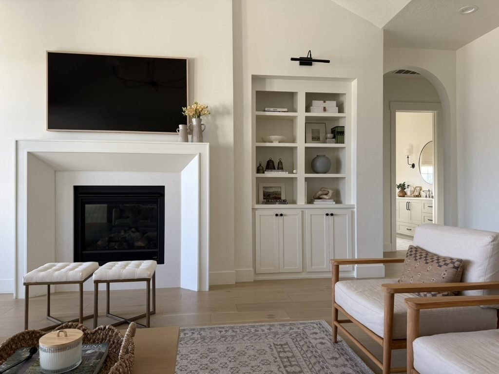 Living room fireplace flanked by white built-in cabinetry and open shelving