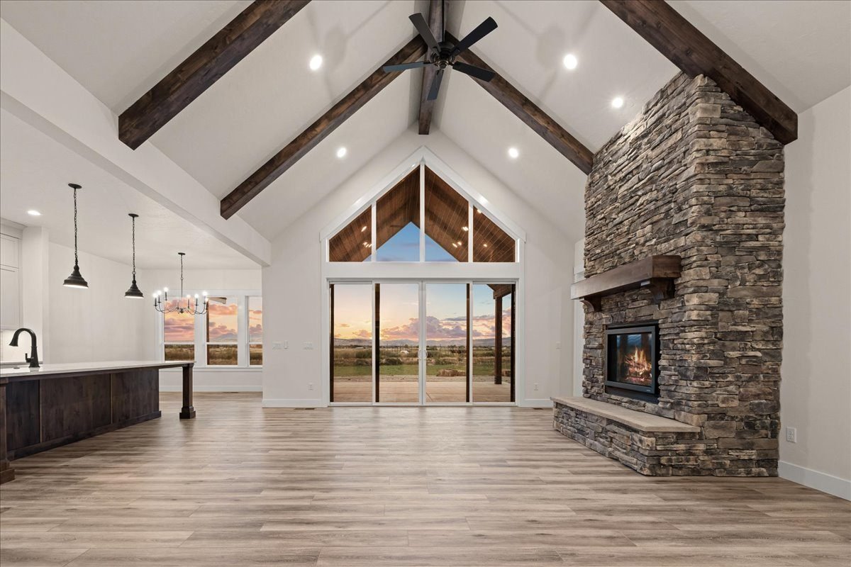 Vaulted great room with exposed beams and a floor-to-ceiling stone fireplace
