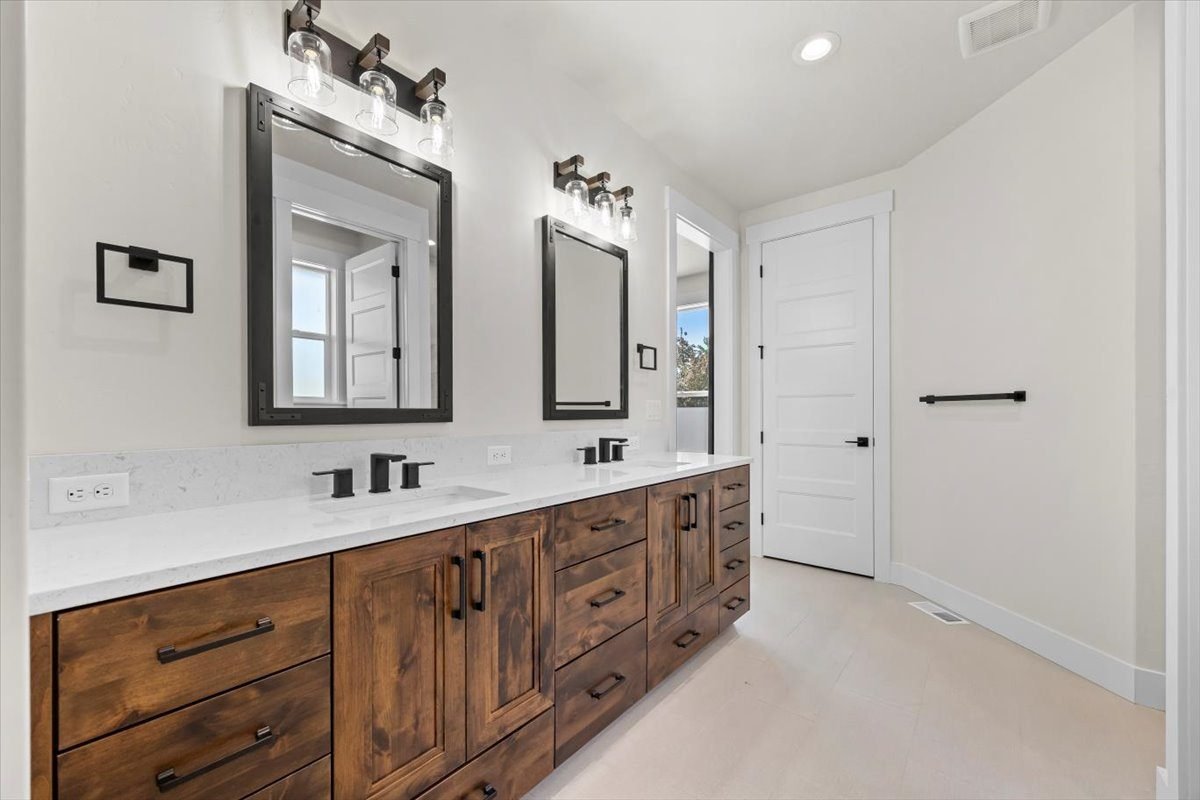 Double vanity with dark wood cabinetry and framed mirrors in a primary bathroom