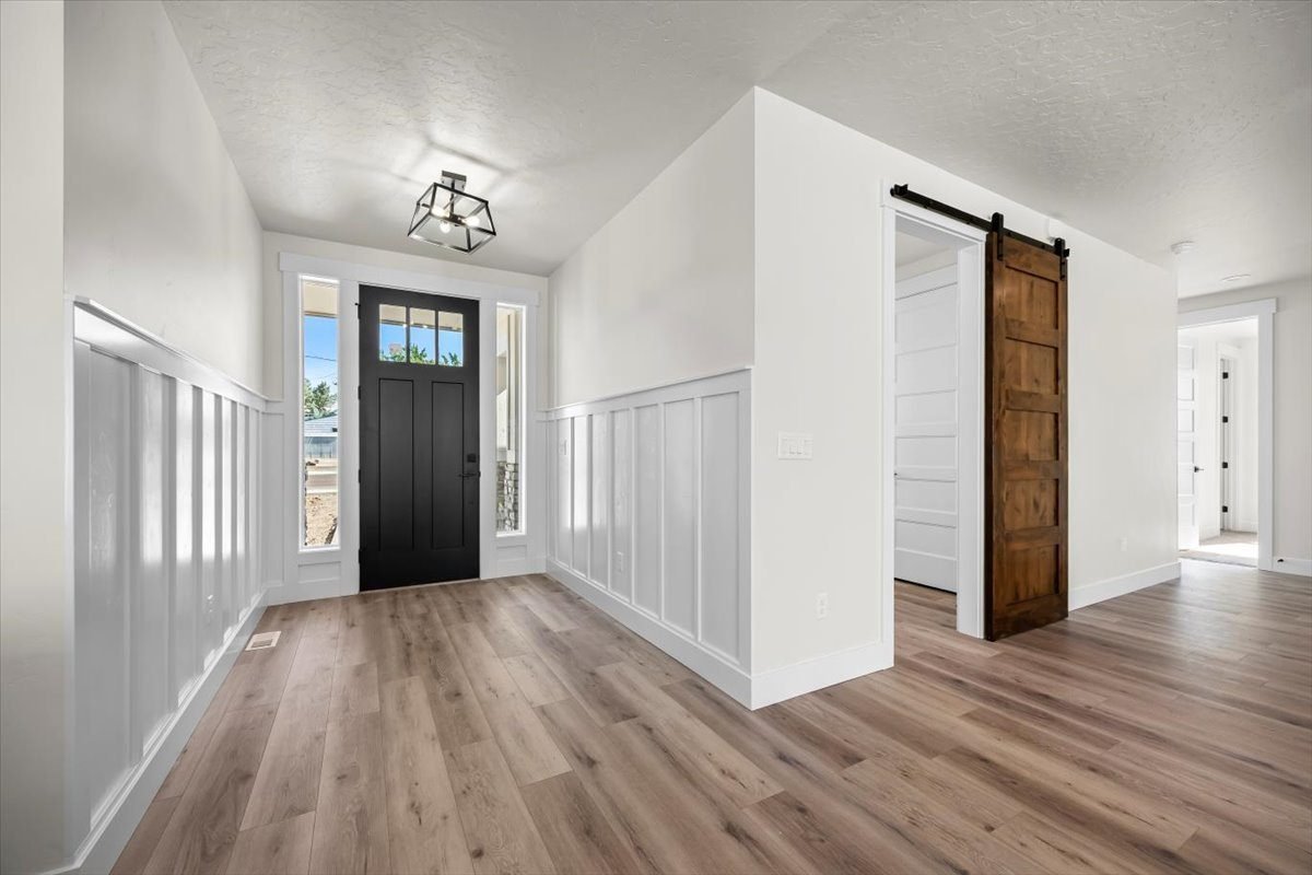 Entry with wainscoting, wide plank floors and a sliding barn door