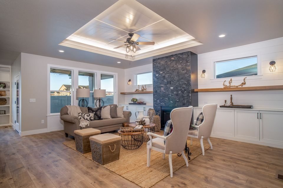 Living room with a tray ceiling and a stone fireplace