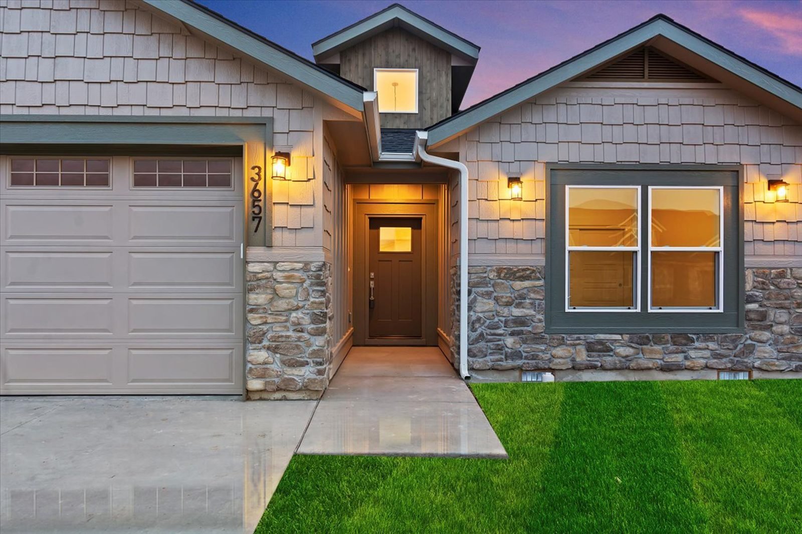 Covered entry and garage of a custom home at dusk